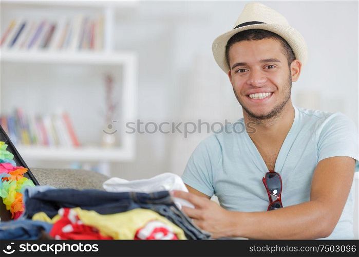 portrait of happy young man packing a suitcase