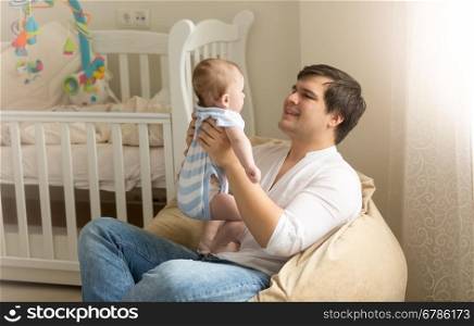 Portrait of happy young man playing with his baby at bedroom