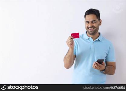 Portrait of happy young man showing credit card during online shopping through Smartphone