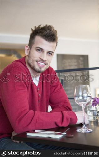 Portrait of happy young man sitting at cafe table