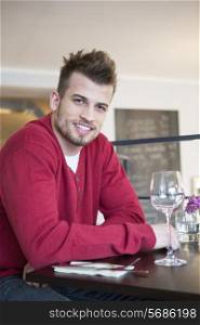 Portrait of happy young man sitting at cafe table