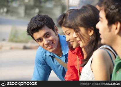 Portrait of happy young man sitting with his friends