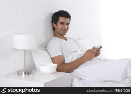 Portrait of happy young man using digital tablet in bed