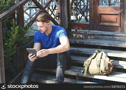 Portrait of happy young man using tablet. Outdoors
