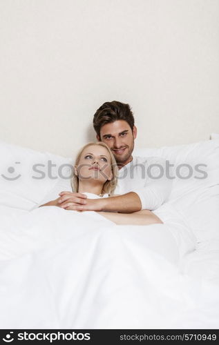 Portrait of happy young man with woman relaxing in bed