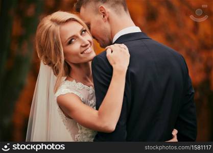 portrait of Happy young married couple in golden yellow fall autumn park. beautiful bride and stylish groom hugging in wedding day.. portrait of Happy young married couple in golden yellow fall autumn park. beautiful bride and stylish groom hugging in wedding day