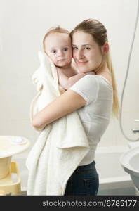 Portrait of happy young mother holding her baby after having bath