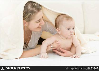 Portrait of happy young mother lying with her 6 month son on bed