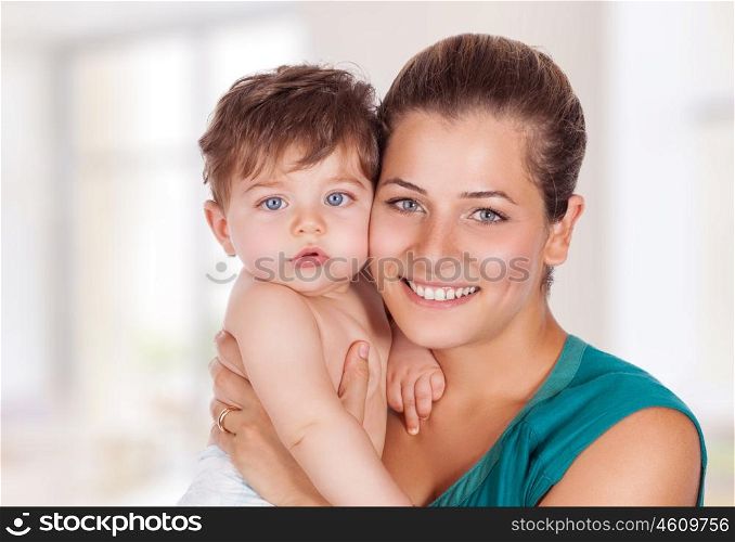 Portrait of happy young mother with cute little son at home, with pleasure spending time together, enjoying motherhood