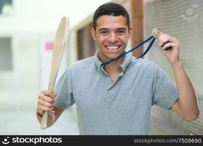 portrait of happy young sportsman showing his medal