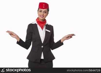 Portrait of happy young stewardess indicating exits isolated over white background