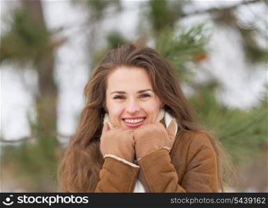 Portrait of happy young woman against fir-tree in winter outdoors