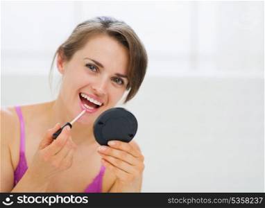 Portrait of happy young woman applying makeup