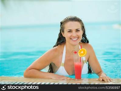 Portrait of happy young woman at pool with cocktail