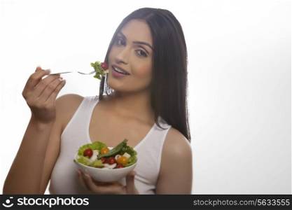 Portrait of happy young woman eating salad of lettuce, cherry tomatoes and mushrooms