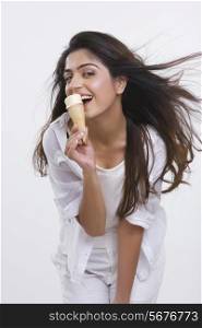 Portrait of happy young woman enjoying ice-cream cone isolated over white background
