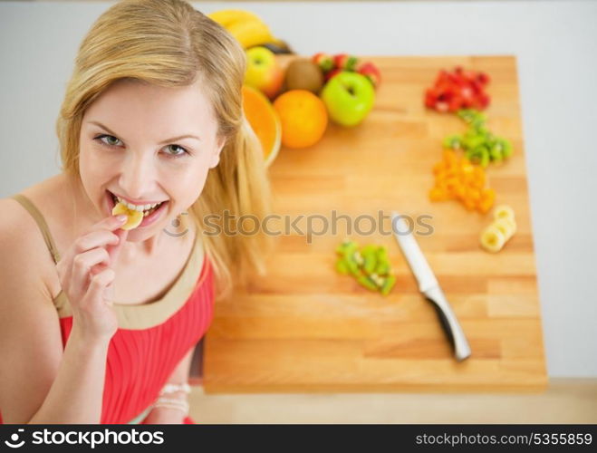 Portrait of happy young woman having a bite while cutting salad