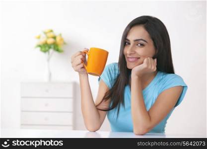 Portrait of happy young woman having coffee at home