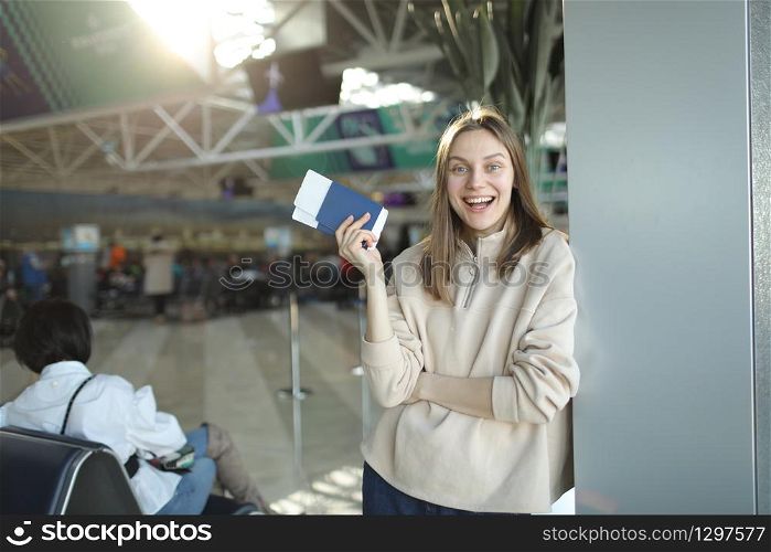 portrait of happy young woman holding passport and boarding pass at airport.. portrait of happy young woman holding passport and boarding pass at airport