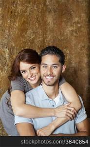 Portrait of happy young woman hugging man from behind