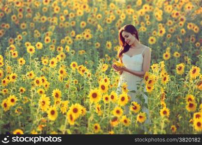 Portrait of happy young woman in a field of sunflowers; copy space