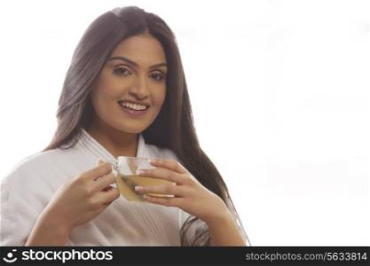 Portrait of happy young woman in bathrobe drinking tea