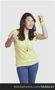 Portrait of happy young woman in casuals wearing Indian tricolor bangles over white background