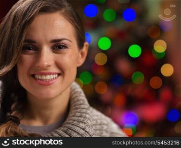 Portrait of happy young woman in front of Christmas lights