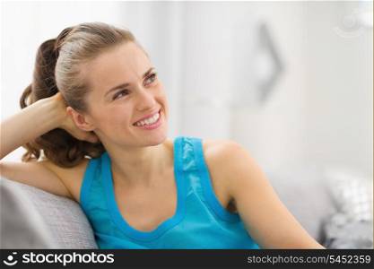 Portrait of happy young woman in living room looking on copy space