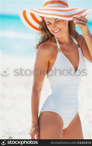 Portrait of happy young woman in swimsuit and beach hat at seaside