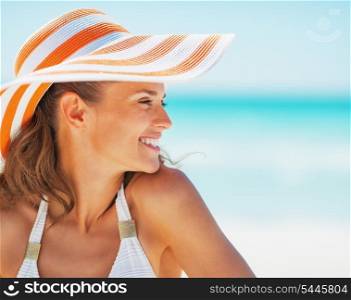 Portrait of happy young woman in swimsuit and beach hat looking on copy space