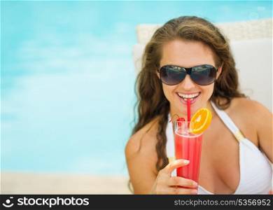 Portrait of happy young woman in swimsuit drinking cocktail