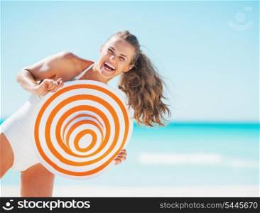 Portrait of happy young woman in swimsuit with beach hat having fun time on beach