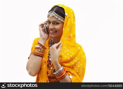 Portrait of happy young woman in traditional wear using cell phone over white background