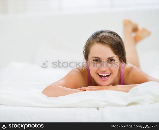 Portrait of happy young woman laying on bed