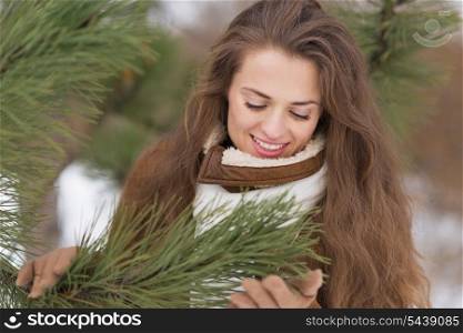 Portrait of happy young woman near fir-tree