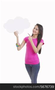 Portrait of happy young woman pointing at thought bubble over white background