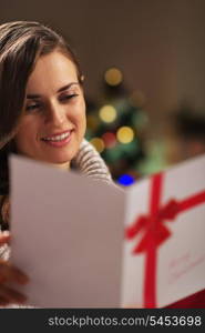 Portrait of happy young woman reading christmas postcard