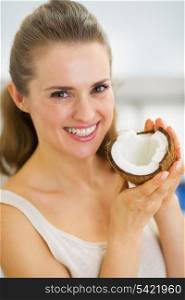 Portrait of happy young woman showing coconut