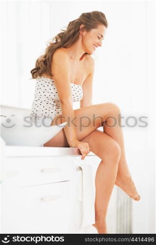 Portrait of happy young woman sitting in bathroom
