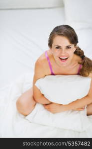 Portrait of happy young woman sitting on bed