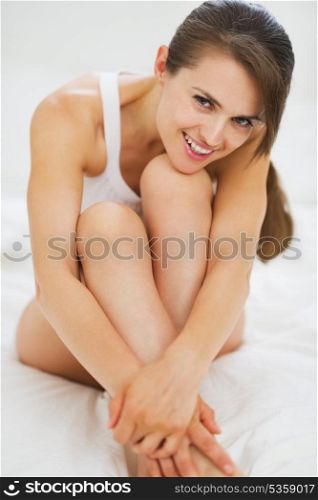 Portrait of happy young woman sitting on bed