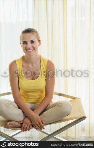Portrait of happy young woman sitting on modern chair