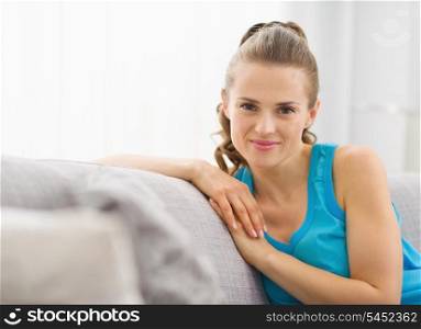 Portrait of happy young woman sitting on sofa in living room