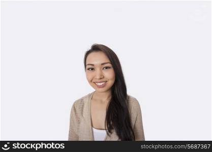 Portrait of happy young woman standing against gray background