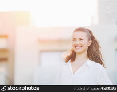 Portrait of happy young woman standing in front of house building