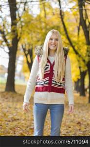 Portrait of happy young woman standing in park during autumn