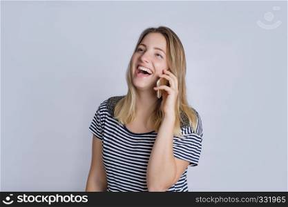 Portrait of happy young woman talking on phone in studio. Isolated on gray background