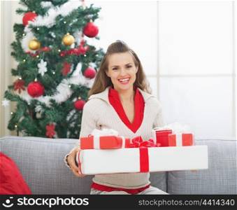 Portrait of happy young woman with christmas present boxes near christmas tree