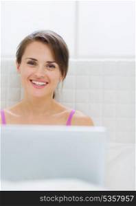Portrait of happy young woman with laptop in bed